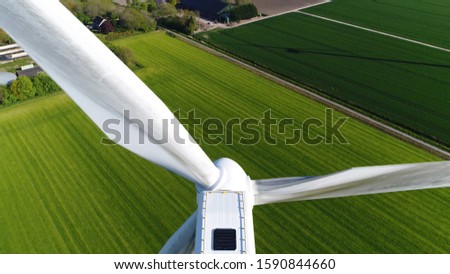 Aerial close up photo of wind turbine providing sustainable energy by spinning blades the power also known as renewable is collected from resources green field meadow in background Royalty-Free Stock Photo #1590844660