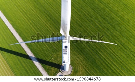 Aerial photo of wind turbine providing sustainable energy by spinning blades the power also known as renewable is collected from resources green field meadow in background