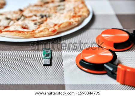 on the table are a usb flash drive headphones and pizza