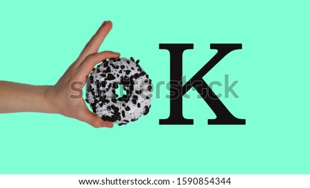 OK in the child's hand. the girl holds a donut in her hand on a menthol background. Obesity, overweight. The danger of obesity, the harm of donuts and cake for the figure and body, baking, cake and sw