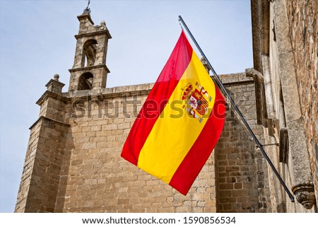 Flag of Spain in front of an old church in Cáceres