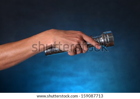 Hand with Flashlight on the dark background