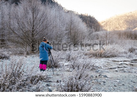 Back view of photographer taking photo a frost morning amazing scenery in Kamikochi. Early winter season in mid-November is located in the Hida Mountains,the Northern Alps of the Japan Alps, Japan.