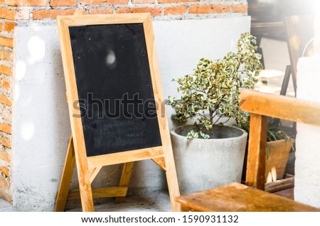 Chalk board wooden frame sign in front of store, shop, restaurant on street. Vintage welcome sign mockup with lighting. Menu mockup in front of restaurant. Black board, Chalkboard with copy space.