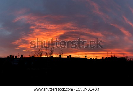 A silhouette of a cityscape with trees under the beautiful sunset sky