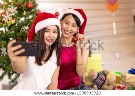 Two Asian women wearing red hats are taking pictures on the phone on New Year's Eve.