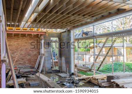 Renovation projects. Building of extension of the existing house, unfinished wooden roof structure, brick walls, scaffolding, selective focus Royalty-Free Stock Photo #1590934015
