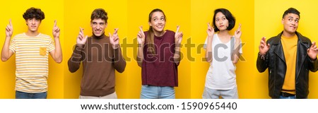 Set of people over isolated yellow background with fingers crossing and wishing the best