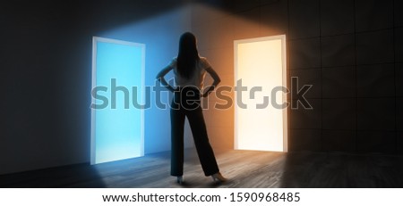 Young woman in dark room with two open doors. Concept of choice Royalty-Free Stock Photo #1590968485