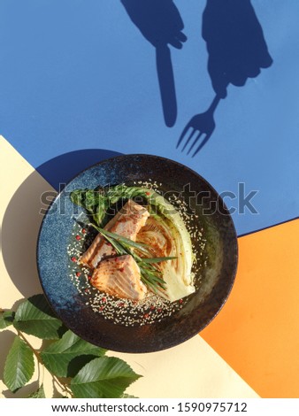 A gourmet culinary dish of salmon steak on white cabbage with sesame seeds. Bright color background, creative restaurant concept