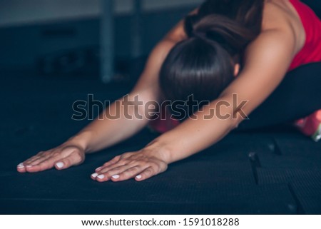 Slim fit muscular brunette woman exercise in gym, lifting weights and doing pilates. Picture with dark evening mood and film color grading