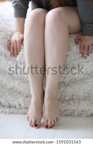 women bare legs and feet with red pedicure close up photo on bed background