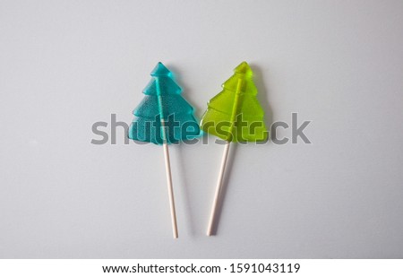 Green Christmas candy canes with wooden sticks. Christmas trees on a white background. Holiday picture. New year wallpapers. Post card. Composition of sweets. Two conifers.