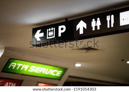 A directional signboard, indicating direction to an elevator, parking lot, toilet, food court, canteen, and atm