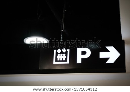 A directional signboard, indicating direction to an elevator and parking lot
