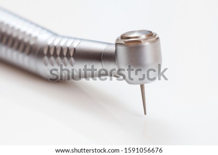 Head of high-speed dental handpiece with bur on white background. Dental instruments for dental treatment. Medical tools. Close-up view. Shallow depth of field. Focus on the bur. Royalty-Free Stock Photo #1591056676