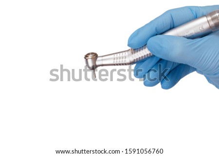 Dentist's hand in a latex glove with new high-speed dental handpiece on white isolated background. Medical tools concept. Royalty-Free Stock Photo #1591056760