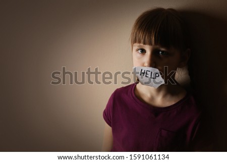 Sad little girl with sign HELP on beige background, space for text. Child in danger