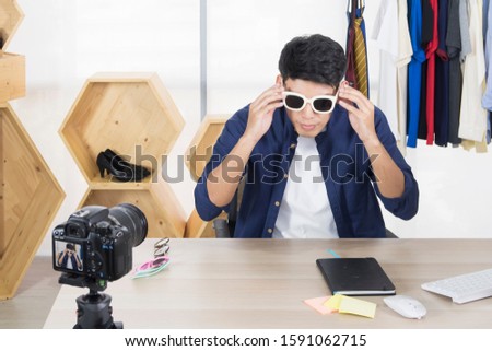Young Happy Asian male wearing white sunglass while recording video for sharing content with internet subscribers. Business, startup, e-commerce, social media, marketing online, vlog concept.