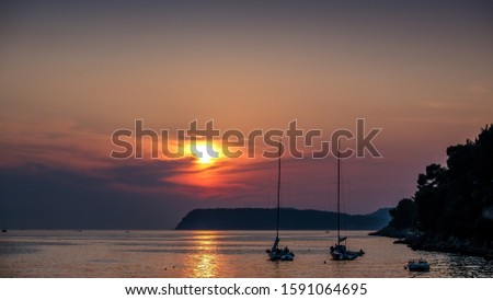 Sunset behind two boats on Sunset Beach Dubrovnik, Croatia