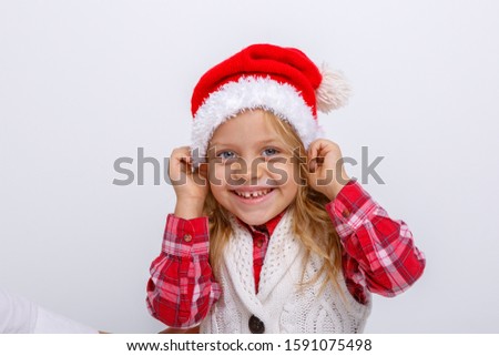 portrait of smiling little blonde girl in Santa hat on white and yellow backgrounds