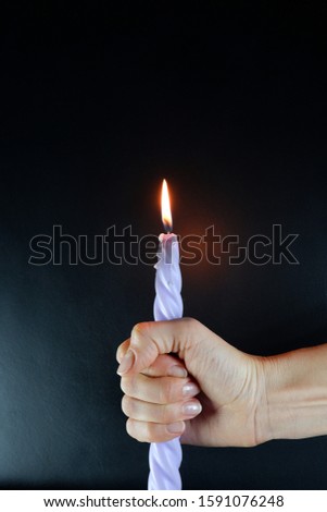 On a black board a burning candle in his hand, copy space