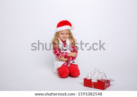 wicked little blonde girl in Santa hat with gift in hand isolated on white background
