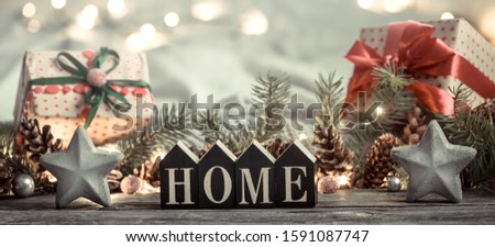 Festive background with lights and the inscription home on a wooden table. With festive decor items. The concept of Holiday and home comfort.
