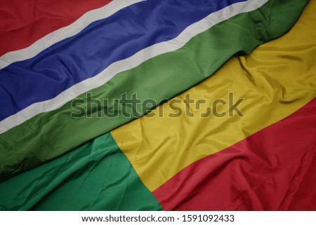waving colorful flag of benin and national flag of gambia. macro