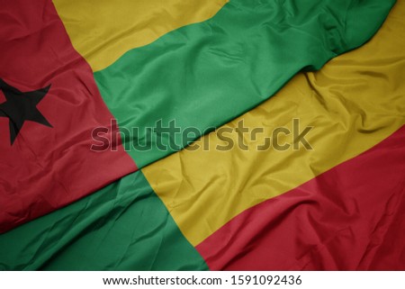 waving colorful flag of benin and national flag of guinea bissau. macro