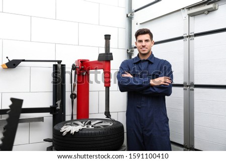 Man near tire fitting machine at car service