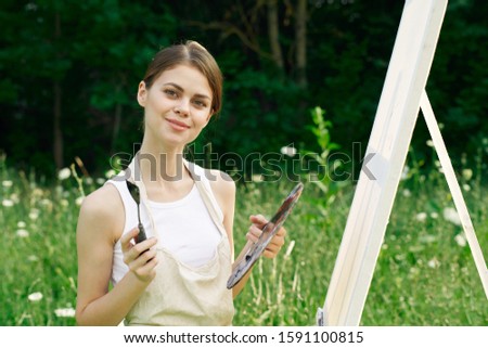 young woman draws a picture in the fresh air
