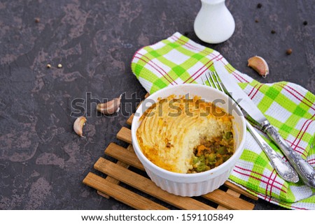 Portion shepherds pie or traditional British potato casserole with minced meat and vegetables on a dark brown concrete background. Potato Recipes. Copyspace.