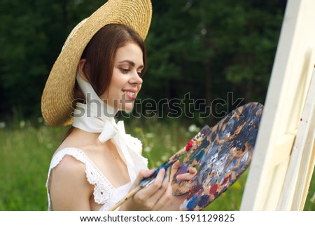young woman draws a picture on canvas an easel