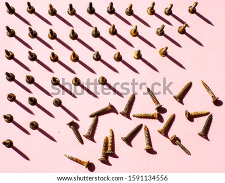 Screws placed vertically and horizontally on pink background