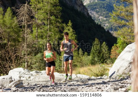 Photo of young sporty couple doing running in the mountains