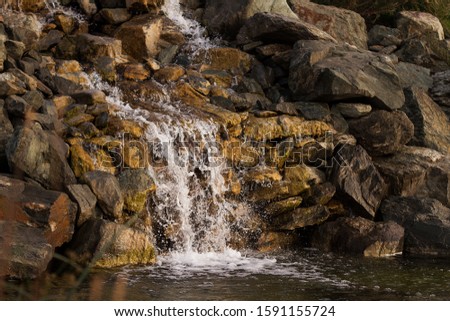 A small cascade of a waterfall. Large stones around the waterfall. Selective focus.