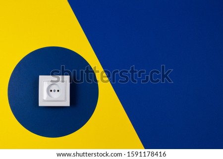 White electrical socket on geometric yellow and blue navy color background