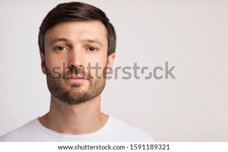 Portrait Of Confident Man Looking At Camera Posing Over White Studio Background. Copy Space