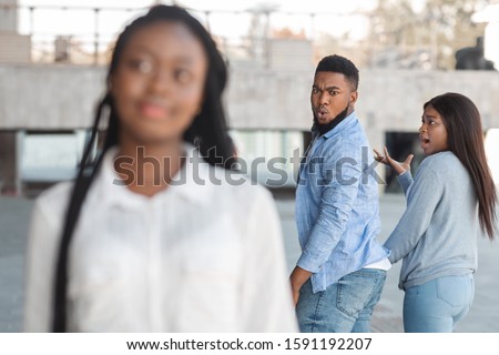Distracted african american guy turning around and looking to another woman while walking with his girlfriend Royalty-Free Stock Photo #1591192207