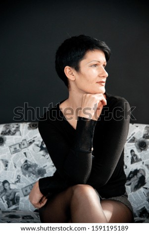 a girl with short black hair in a black tank top and a gray skirt