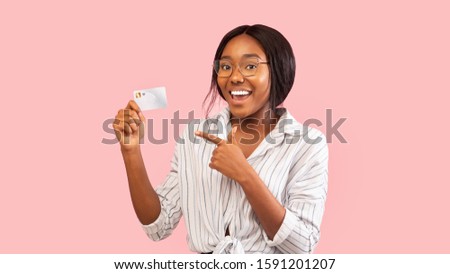 Positive Black Girl Showing Credit Card Pointing Finger Recommending Bank Services Standing Over Pink Studio Background. Panorama