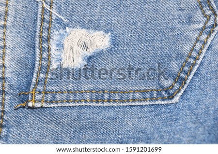 Jeans texture with ripped destroyed torn, blue denim hole and threads background