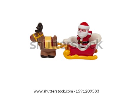 Children's toy - Santa Claus with a bag of gifts stands in a sleigh pulled by a deer and waves his hand in greeting on a white isolated background.