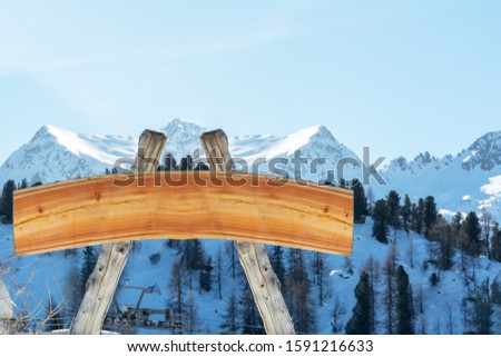 Blank billboard for outdoor advertising from logs and a wooden board on a ski slope against the backdrop of the mountains. The concept of advertising, landscape, sport