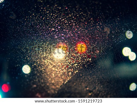 water drops and splashing on glass windshield in dark blue night , look like stars in universe