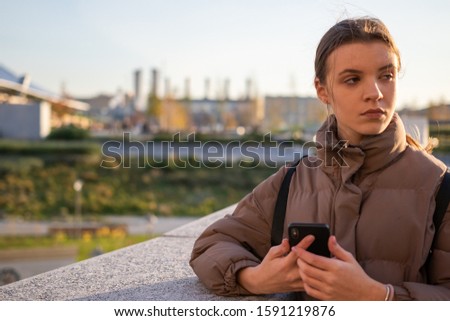Young girl with a phone on the street, blurred background of Moscow streets.