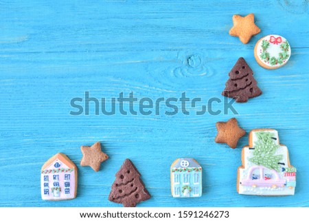Set of cute homemade gingerbread cookies for christmas on wooden blue background. New year biscuits with beautiful iced decoration on textured turquoise backdrop. Traditional gingerbread cookies 
