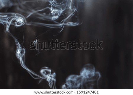 Image of backlit puffs of smoke, on a dark background, close-up.