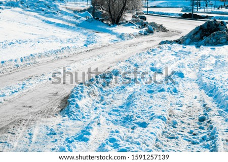 A pile of dirty snow on the side of the road. Uncleaned winter city road. Snowdrifts of snow on the road. Bad weather for driving. Winter city road transport. Winter path in the snow. 